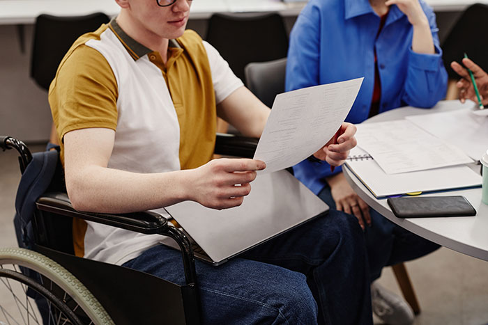 Teen discussing parenting challenges, reading documents in a group meeting.