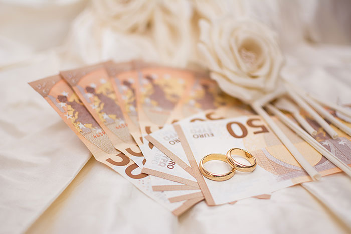 Wedding tax concept with euro bills and wedding rings on a white fabric, symbolizing financial aspects of a wedding.