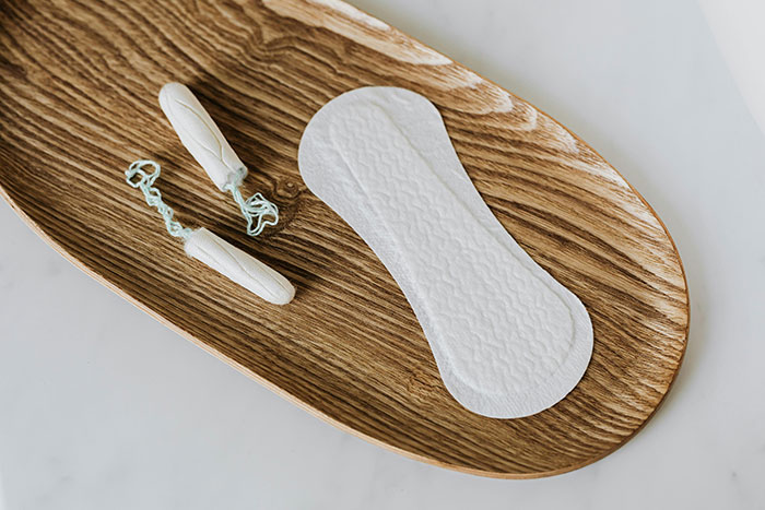 Tampons and a sanitary pad on a wooden tray, representing early motherhood experiences.
