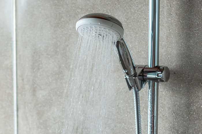 Showerhead with running water, symbolizing uncomfortable explanations of early motherhood.
