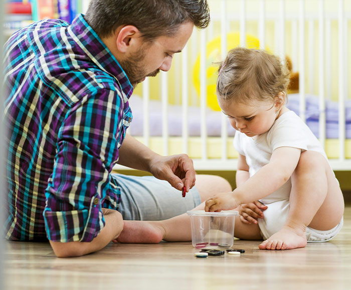 Father spending time with child on the floor, illustrating parenting and financial support for kids.