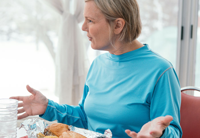 Woman in blue shirt gesturing during a conversation about husband supporting kids financially.