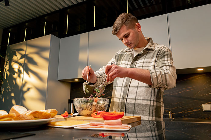Man in a kitchen preparing a salad, expressing frustration about heavy, fatty meals. Man in a kitchen preparing a salad, expressing frustration about heavy, fatty meals.