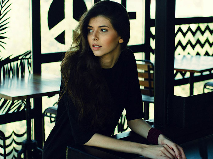 Woman sitting in a dimly lit cafe, looking to the side.