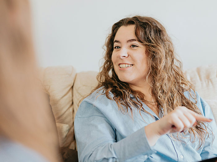 Woman in a blue shirt smiling while sitting, related to exposing a mistress's past.