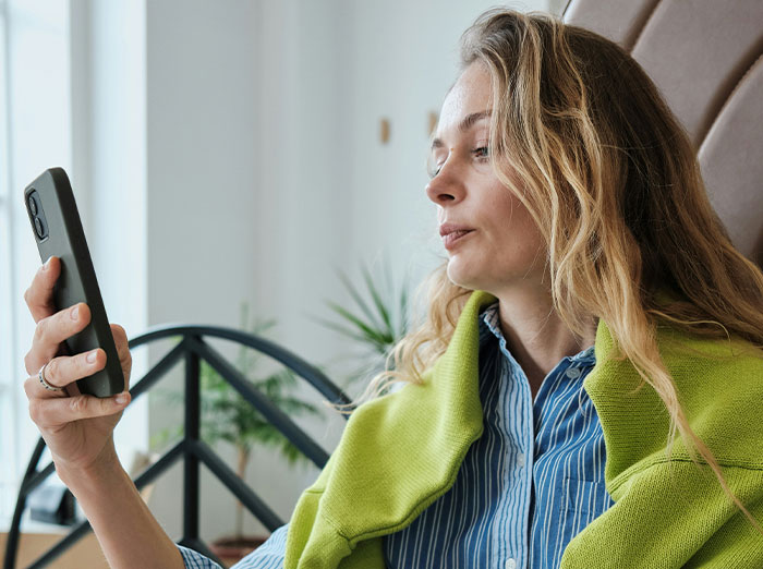 Woman looking at her phone, contemplating a past experience related to cheating and exposure.