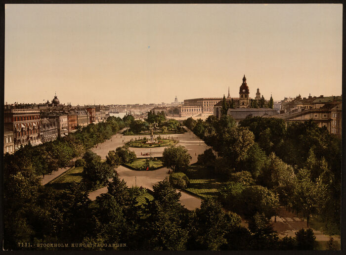 Early color photo of a park with gardens in Stockholm, showcasing historic architecture and cityscape from 100 years ago.
