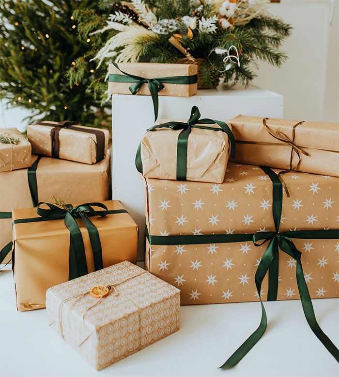 Christmas presents stacked under a decorated tree, wrapped in star-patterned and plain paper with green ribbons. Christmas presents stacked under a decorated tree, wrapped in star-patterned and plain paper with green ribbons.