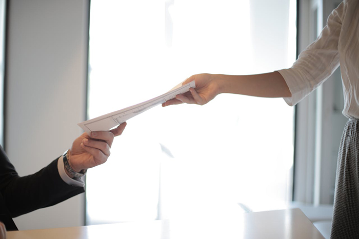 A person handing over documents, highlighting background check issues in the hiring process.