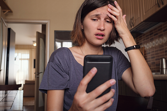 Woman looking upset while reading a message on her phone, testing the impact of calling her by a mean name.