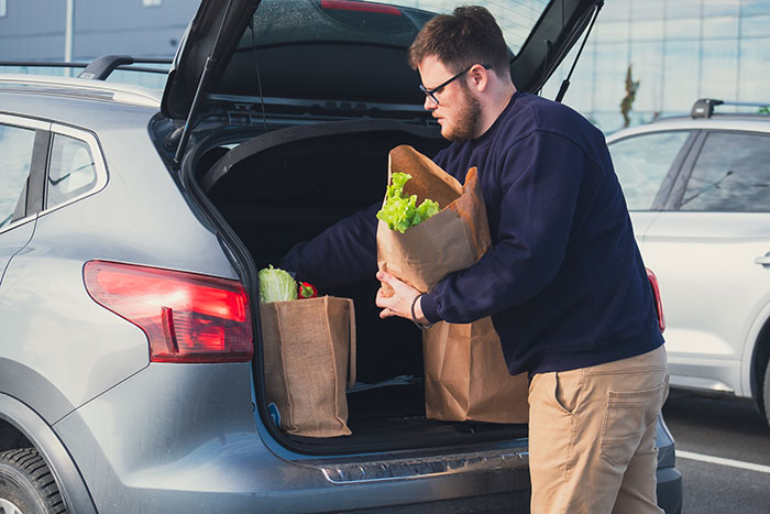 Shopper loads groceries into a car at Costco parking lot. Shopper loads groceries into a car at Costco parking lot.