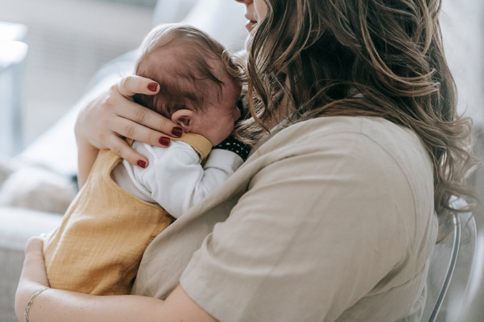 Woman holding a baby, highlighting shared parenting responsibilities during maternity leave.
