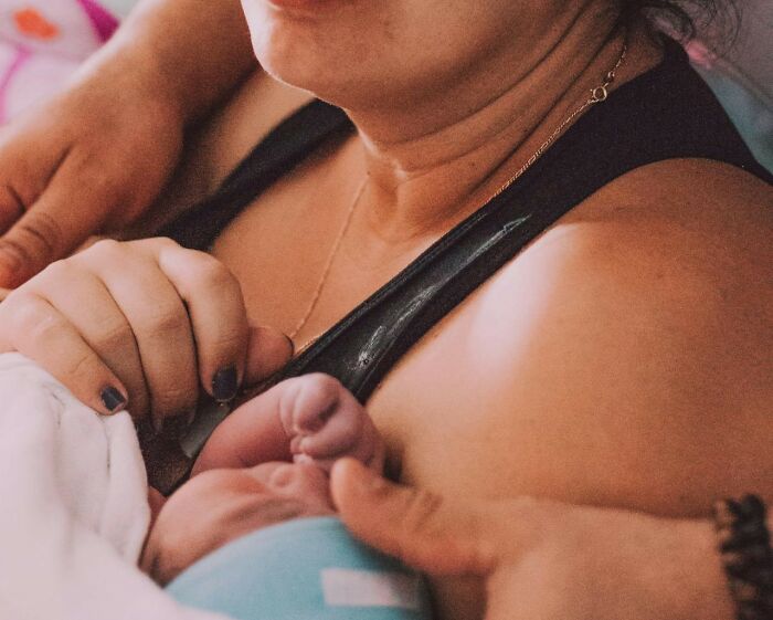 A mother gently holds her newborn in her arms, surrounded by warmth and tenderness.