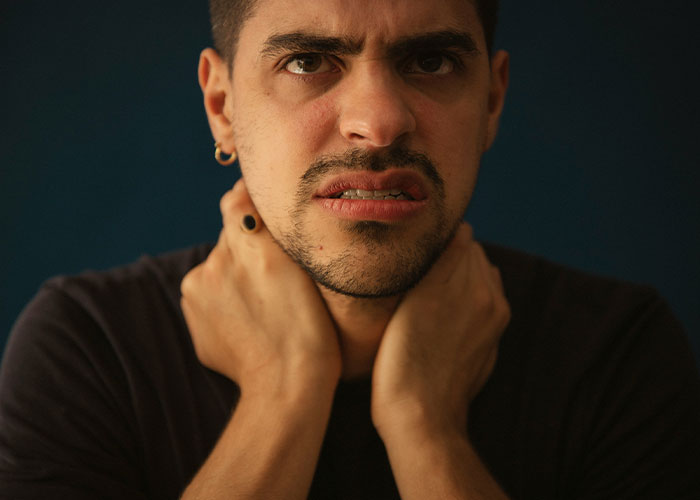 Man looking regretful, holding his neck, symbolizing secrets revealed by drunk people.