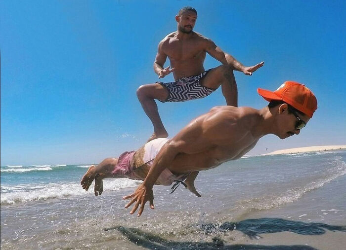 Two men at the beach, one jumping over the other, could be an album cover concept.