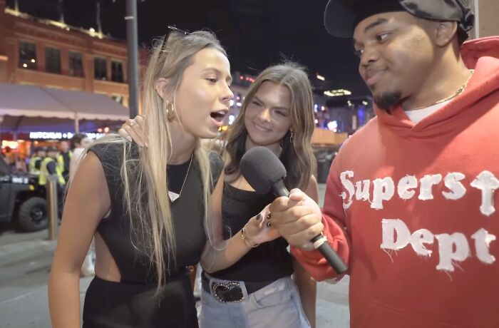People discussing trends for 2024 on the street; two women and a man with a microphone at night.