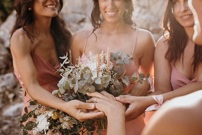 Bridesmaids in pink dresses holding bouquets at a wedding.