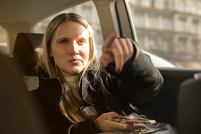 Woman in a car pointing forward, holding a phone, representing sweet revenge and fat-shaming defense. Woman in a car pointing forward, holding a phone, representing sweet revenge and fat-shaming defense.