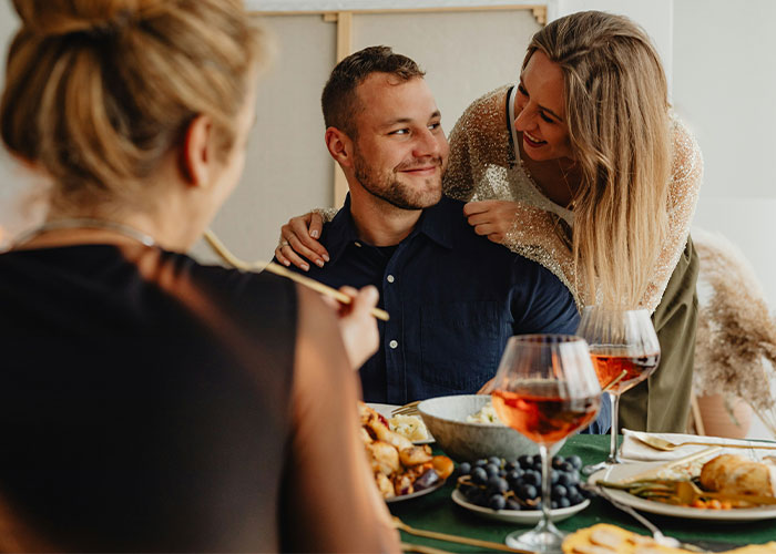 A group of friends enjoying a meal, with wine glasses on the table, sharing secrets.