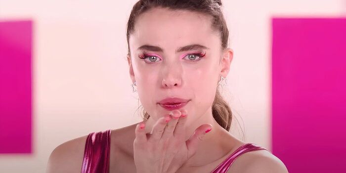 Woman in pink outfit with pink eyeshadow, looking emotional; represents trends people want to avoid in 2024.