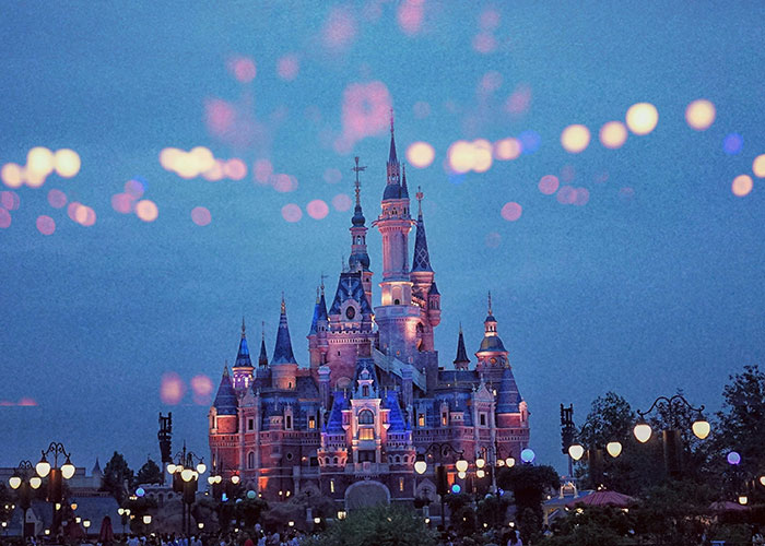 A beautifully lit castle at night, reflecting an enchanting atmosphere with blurred lights in the sky.