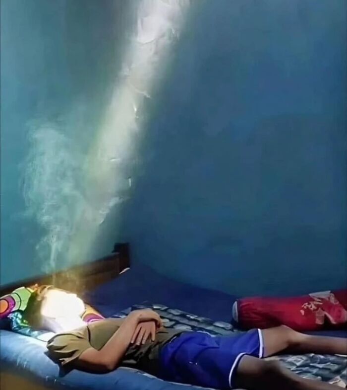 Person lying on a bed with a beam of light illuminating their face, resembling an album cover.
