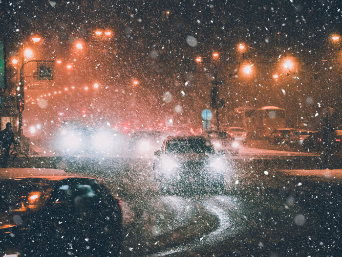 Snowy city street at night with car headlights glowing, illustrating crazy stories.