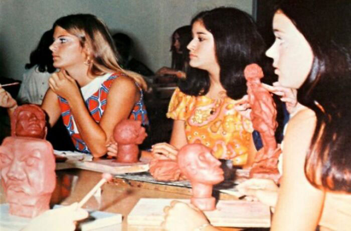 Students sculpting clay figures in a 1970s high school art class, showcasing '70s fashion and classroom ambiance.