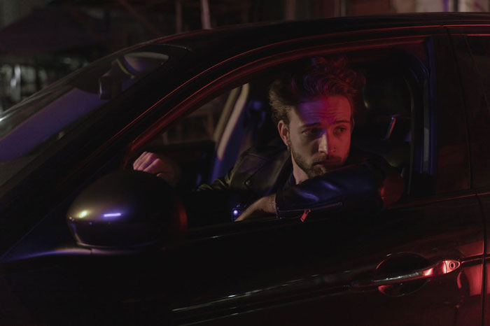 Man sitting in a car at night, looking pensive after a date. 