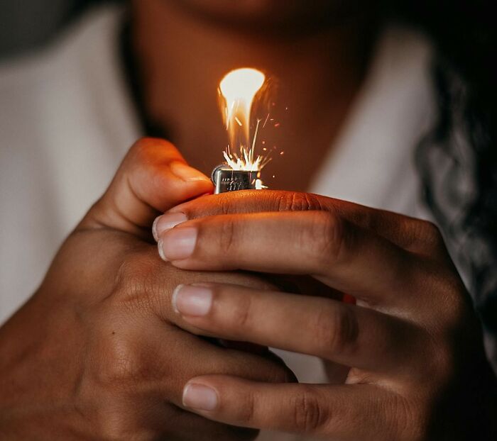Hands holding a lit lighter with sparks, a visual of an unusual fact from the article.