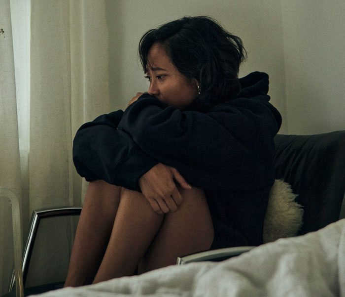 Woman sitting on a chair, looking distressed after discovering career sabotage. Woman sitting on a chair, looking distressed after discovering career sabotage.