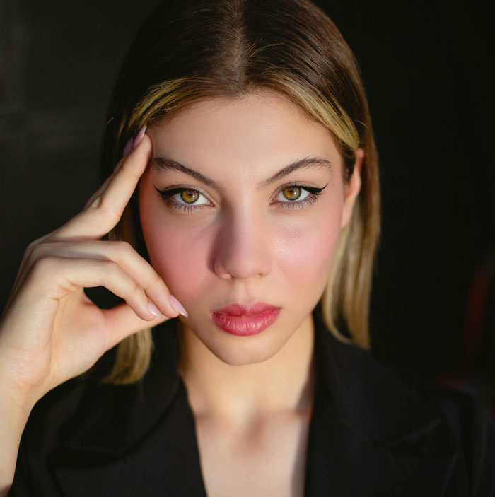 Person with flawless makeup and black blazer, illustrating disliked fashion trends.