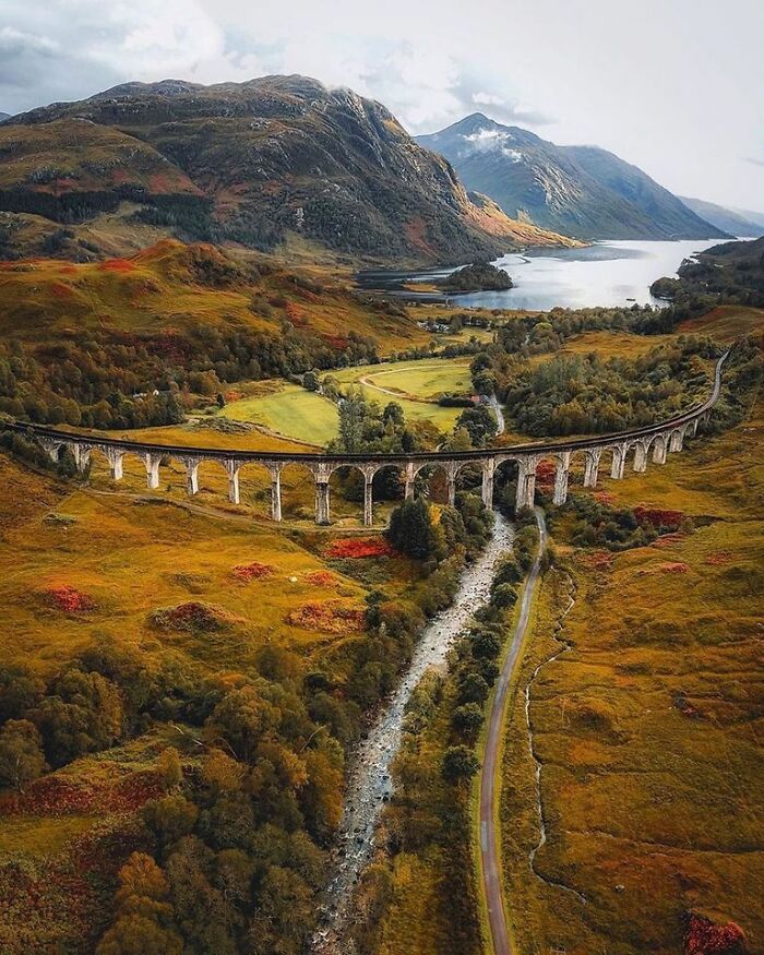 Scenic view of Scotland's lush landscape with a historic viaduct and towering mountains in the background.
