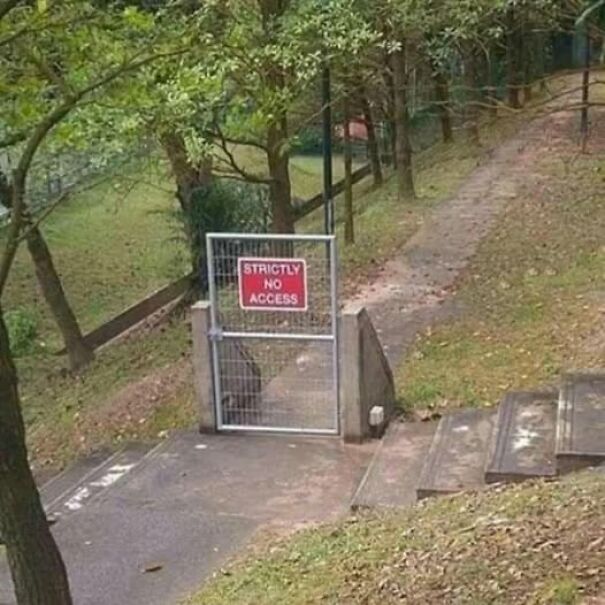 Weird and absurd sign: "Strictly No Access" gate pointlessly blocking a path in a park setting.