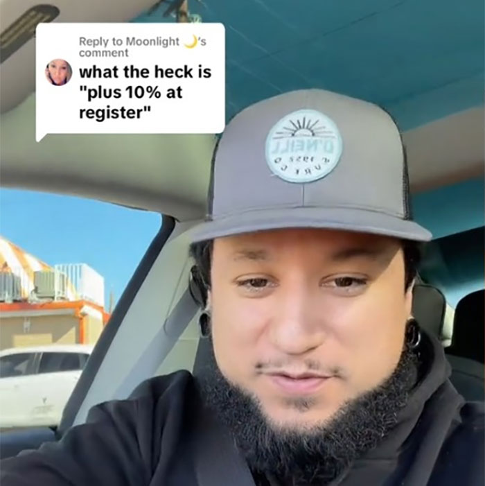 Man in car discusses retail games and a "plus 10% at register" sign, highlighting capitalism's impact. Man in car discusses retail games and a "plus 10% at register" sign, highlighting capitalism's impact.