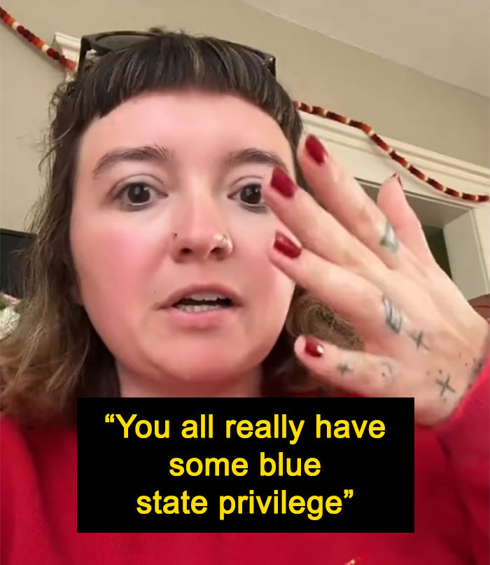 Woman shares thoughts on blue state life, goes viral, wearing a red sweater and showing her painted nails.