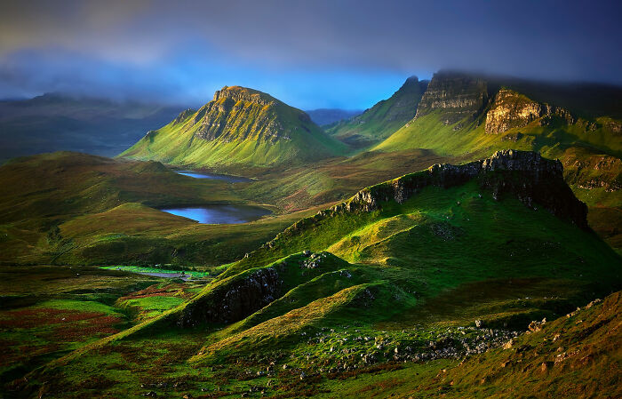 Majestic Scottish landscape with lush green hills and dramatic mountains under a cloudy sky.