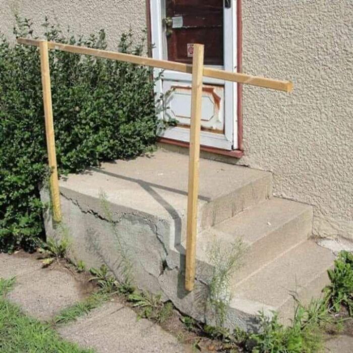 Cheap construction fail featuring a makeshift wooden handrail on c*****d concrete steps.
