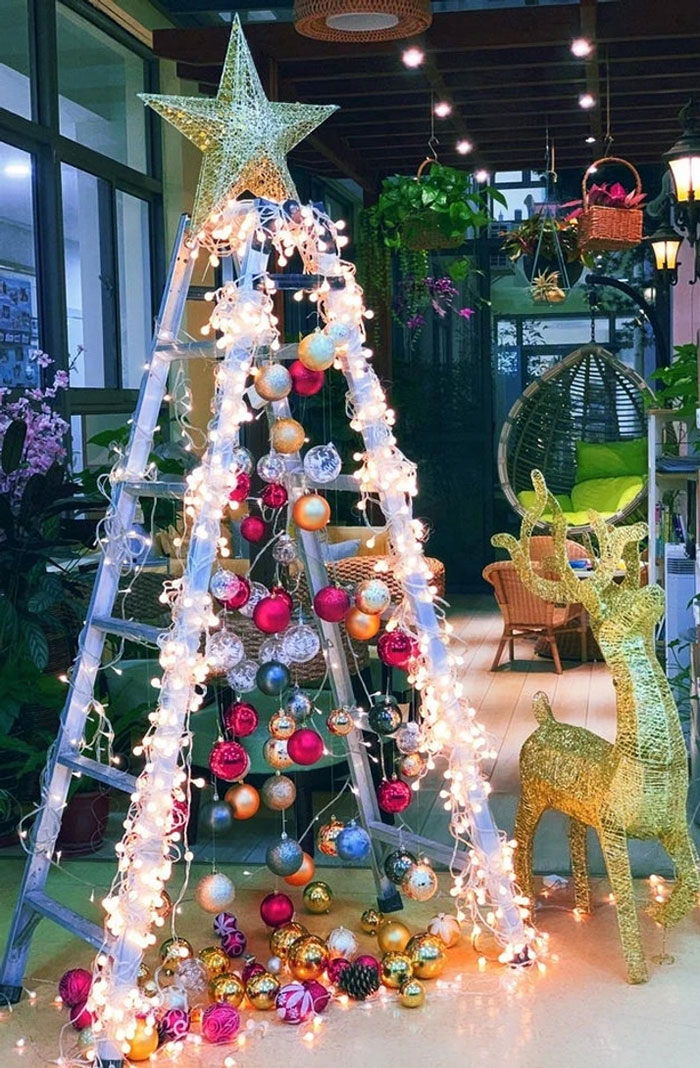 Ladder adorned with lights and ornaments as a creative Christmas tree idea.