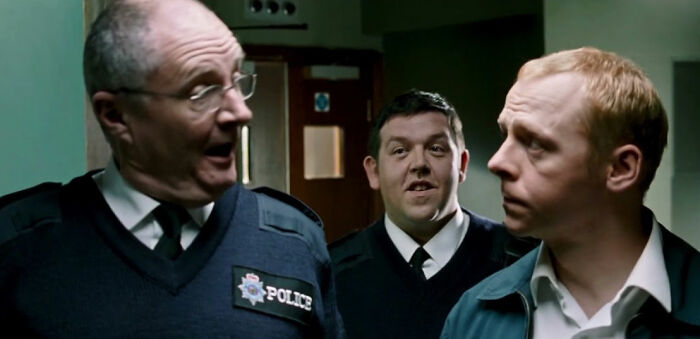 Three men in police uniforms from a comedy movie scene.