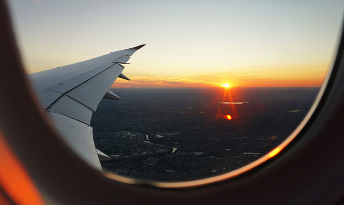 View of airplane wing during sunset, highlighting flight experience.