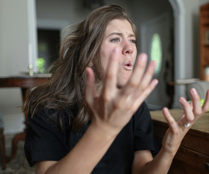 Frustrated woman gesturing angrily in a room, baby formula mentioned as a concern. Frustrated woman gesturing angrily in a room, baby formula mentioned as a concern.