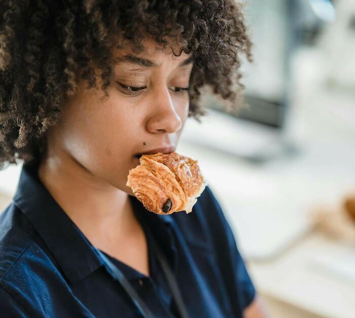 Person contemplating with a pastry, possibly indicating a scenario involving sudden job loss.