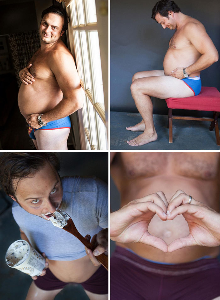 Man humorously posing with a fake pregnancy belly, enjoying snacks, and making a heart shape with hands over stomach.