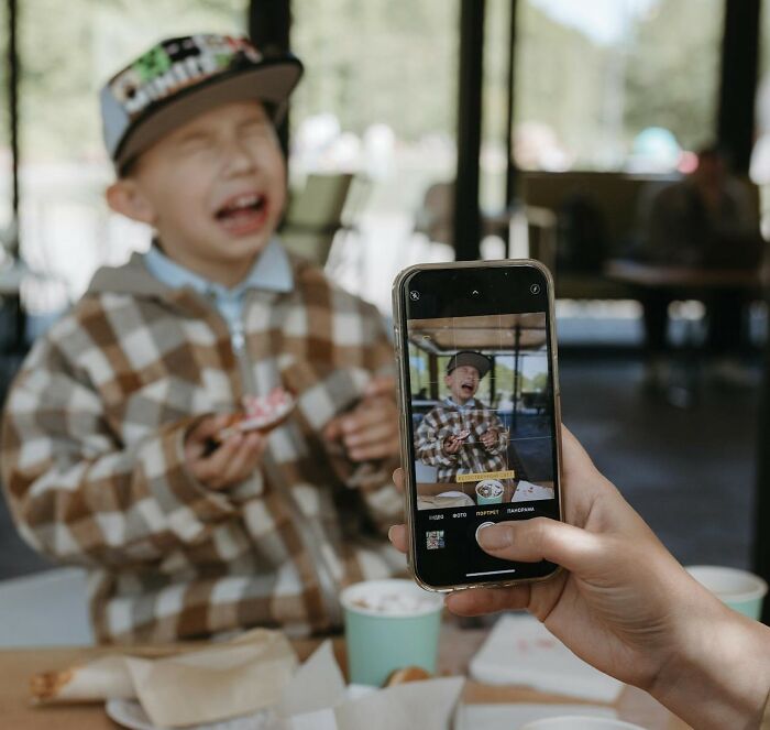 Child in plaid shirt making a funny face while being photographed.