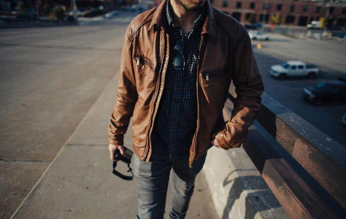 Man in a brown jacket walking on a city street, highlighting security measures and awareness.