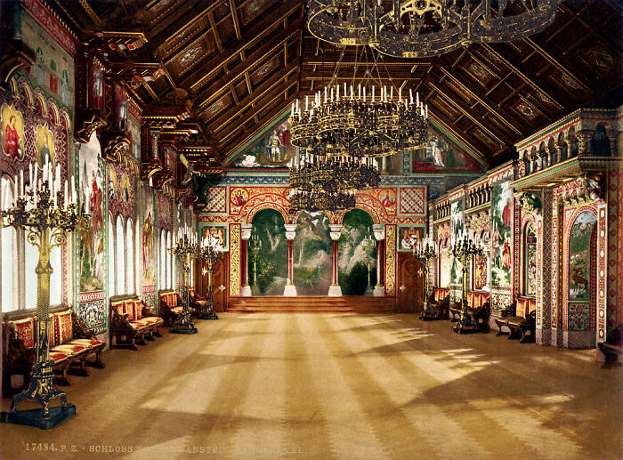An ornate historical hall with chandeliers and colorful murals, displaying world's oldest color photography from 100 years ago.