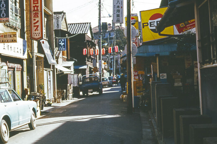 A vibrant 1973 street scene with vintage cars and neon signs, capturing the essence of a bustling urban environment.