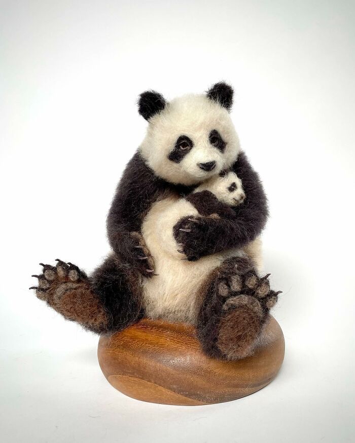 Needle-felted panda hugging a smaller panda, showcasing the artist's skill in creating realistic felted animals.