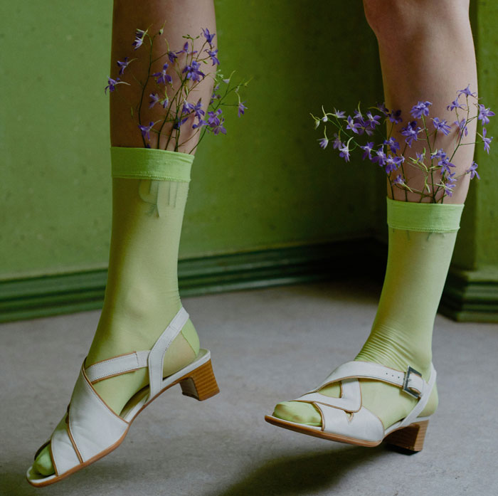 Green socks with sandals and flowers, illustrating a controversial fashion trend.